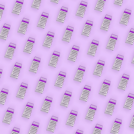 Small stainless steel graters lies on a pastel colored paper. Kitchen accessories. Tools for cooking. Flat lay top view.の写真素材