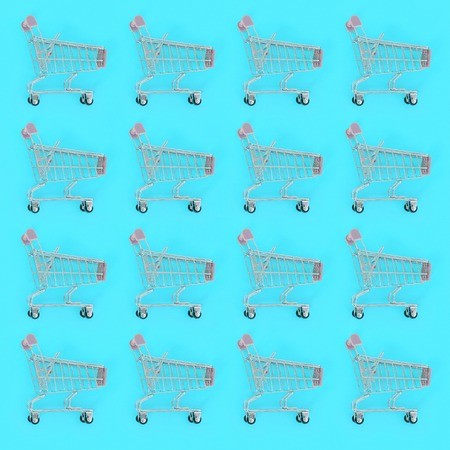 Shopping addiction, shopping lover or shopaholic concept. Many small empty shopping carts perform a pattern on a pastel colored paper background. Flat lay composition, top view.の写真素材