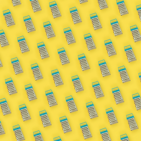 Small stainless steel graters lies on a pastel colored paper. Kitchen accessories. Tools for...
