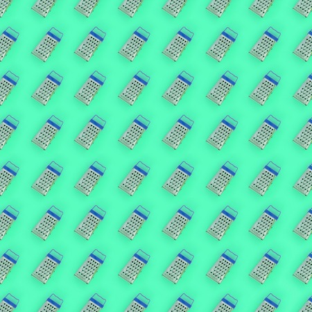 Small stainless steel graters lies on a pastel colored paper. Kitchen accessories. Tools for cooking. Flat lay top view.の写真素材