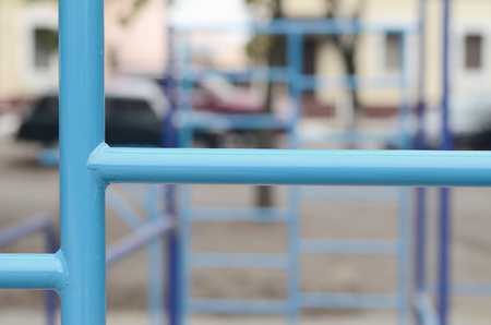 Blue metal pipes and cross-bars against a street sports field for training in athletics. Outdoor athletic gym equipment. Macro photo with selective focus and extremely blurred backgroundの写真素材