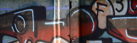 Fragment of graffiti drawings. The old wall decorated with paint stains in the style of street art culture. Colored background texture in warm tones.の写真素材