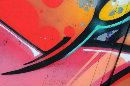 Fragment of graffiti drawings. The old wall decorated with paint stains in the style of street art culture. Colored background texture in warm tones.の写真素材