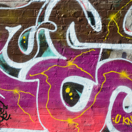 Fragment of graffiti drawings. The old wall decorated with paint stains in the style of street art culture. Colored background texture in warm tones.の写真素材