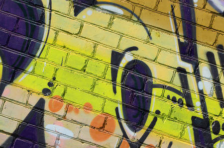 Fragment of graffiti drawings. The old wall decorated with paint stains in the style of street art culture. Colored background texture in warm tones.の写真素材