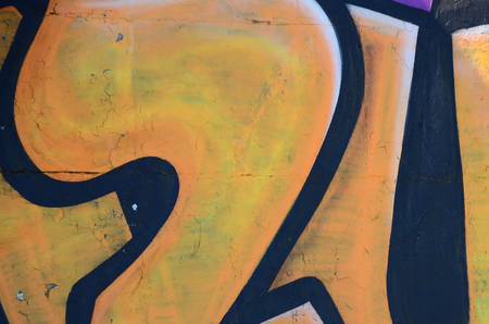 Fragment of graffiti drawings. The old wall decorated with paint stains in the style of street art culture. Colored background texture in warm tones.の写真素材