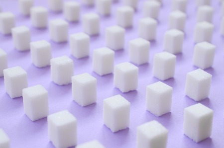 Many small sugar cubes are lined up on a violet background. The concept of diabetes and excess blood sugarの写真素材