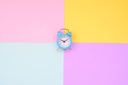 A small blue alarm clock is located between areas of different colors. The concept of time to...