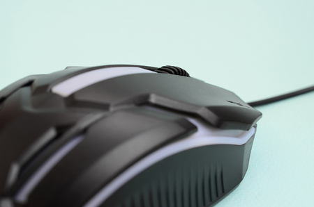 Closeup of a black gaming optical mouse on a blue background. Device for cybersport and online video...