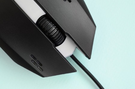 Closeup of a black gaming optical mouse on a blue background. Device for cybersport and online video...