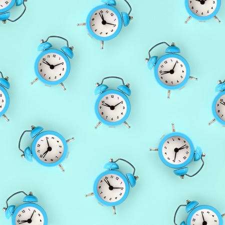 Flat lay retro beautiful new alarm clock on blue color background. Minimal pattern. Top view. Wasting time conceptの写真素材