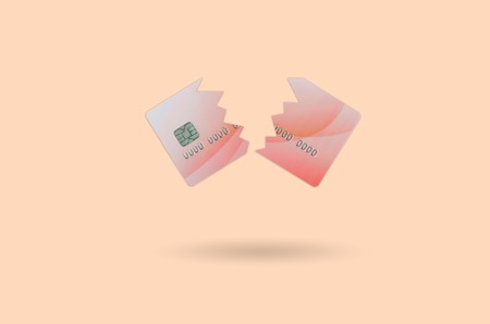 Cut and broken red credit card floating in the pastel orange space. The concept of ban to use...