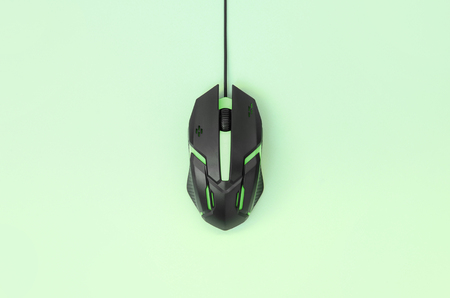 Black gaming optical mouse on a light green background. Device for cybersport and online video games