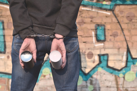 Photo of a young hoodlum caught by the police and shackled in handcuffs. The arrest of a man who...