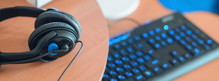 Big black headphones lie on the wooden desktop of the sound designer. Workplace for music creator....