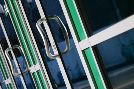 Chrome door handle and glass of modern aluminium door outside the office building