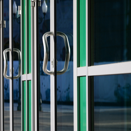 Chrome door handle and glass of modern aluminium door outside the office building