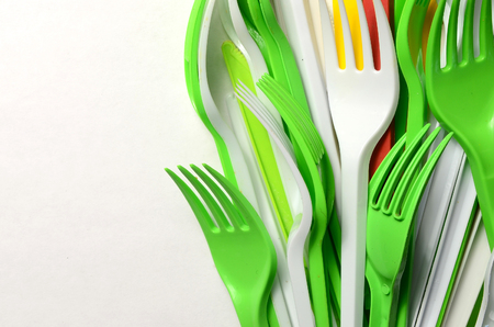 Pile of bright yellow, green and white plastic kitchenware single use appliances on white background