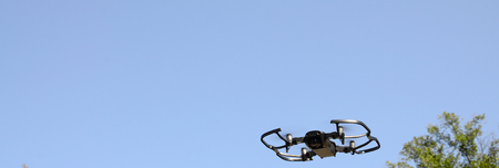 Drone with photocamera take off from land and flying for take aerial photo at sunset evening front of treesの写真素材