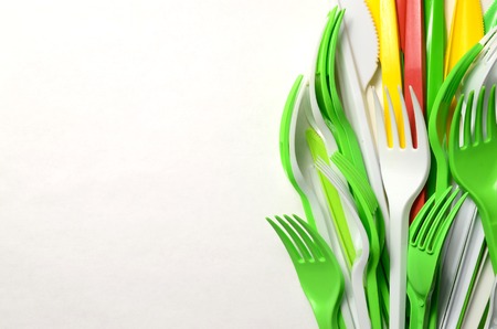 Pile of bright yellow, green and white plastic kitchenware single use appliances on white backgroundの写真素材