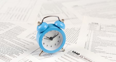 1040 Individual income tax return form with blue alarm clock. Concept of tax period in United States