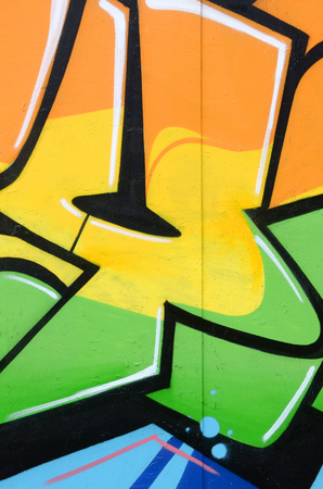 Fragment of colored street art graffiti paintings with contours and shading close up. Background texture of youth contemporary art culture. Orange yellow and green colorsのeditorial素材