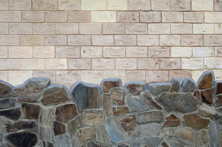 Rustic old beige white brick wall background and worn foundation with shabby brown stonesの写真素材