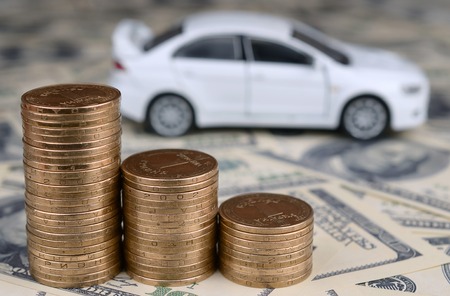 Toy car model at the stacks of golden coins lies on many dollar bills, fixed rate for car loan or saving money for buy car, trade with cash, finance conceptの写真素材