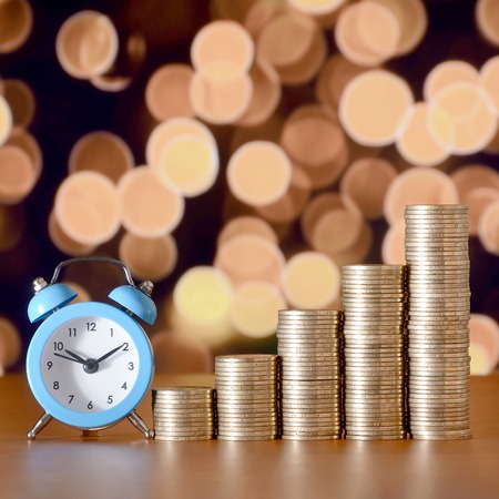 Time for savings money concept, banking and business idea. Alarm clock and Money coin stacks in grow...
