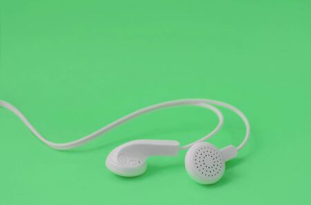 White modern headphones lie on a bright green background. A template for music listening fansの写真素材