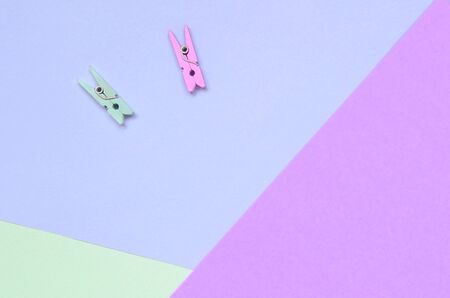 Two colored wooden pegs lie on texture background of fashion pastel violet, turquoise and pink colors paper in minimal concept.の写真素材