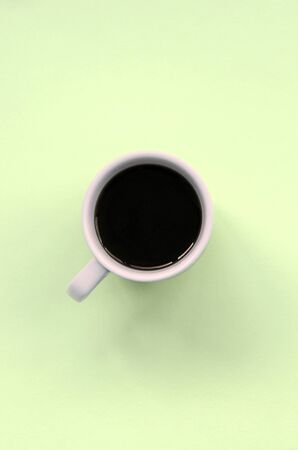 Small white coffee cup on texture background of fashion pastel lime color paper in minimal concept.の写真素材