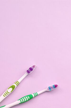 Two toothbrushes lie on a pastel pink background. Top view, flat lay. Minimal concept.の写真素材