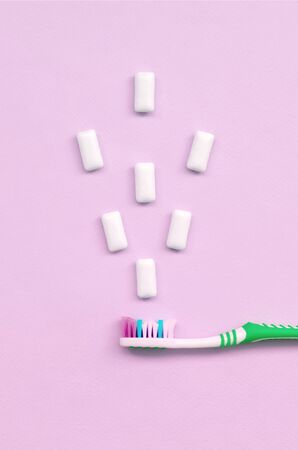 Toothbrush and chewing gums lie on a pastel pink background. Top view, flat lay. Minimal concept.の写真素材