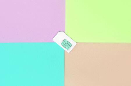 Subscriber identity module. New white SIM card on bright multicolor background. Minimal flat lay top view. Coral pink, lime and blue colorsの写真素材