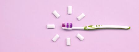 Toothbrush and chewing gums lie on a pastel pink background. Top view, flat lay. Minimal concept.の写真素材