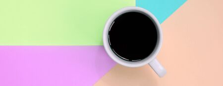 Small white coffee cup on texture background of fashion pastel pink, blue, coral and lime colors paper in minimal concept.の写真素材