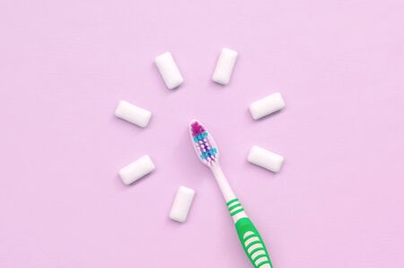 Toothbrush and chewing gums lie on a pastel pink background. Top view, flat lay. Minimal concept.の写真素材