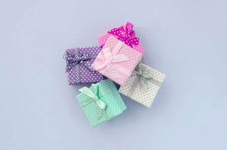 Pile of a small colored gift boxes with ribbons lies on a violet background. Minimalism flat lay top view.の写真素材