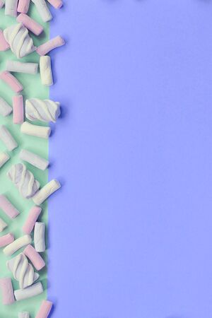 Colorful marshmallow laid out on green and lilac paper background. pastel creative textured framework. minimal.の写真素材