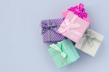 Pile of a small colored gift boxes with ribbons lies on a violet background. Minimalism flat lay top view.の写真素材