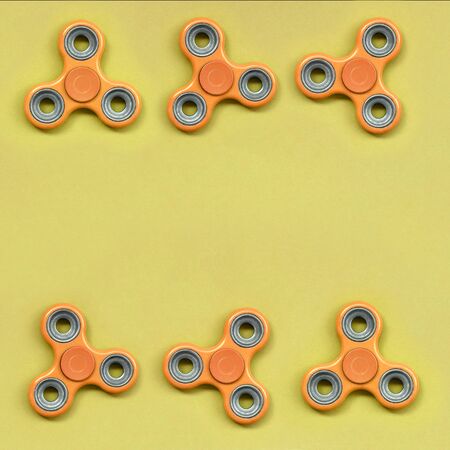 Many orange fidget spinners lies on texture background of fashion pastel orange color paper in minimal concept.の写真素材