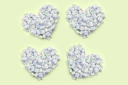 Colorful marshmallow laid out on lime and pink paper background. pastel creative textured hearts....