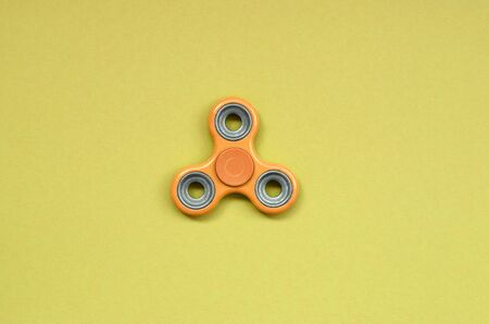 orange fidget spinner lies on texture background of fashion pastel orange color paper in minimal concept.の写真素材