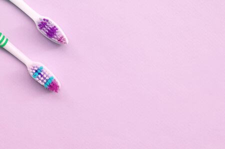 Two toothbrushes lie on a pastel pink background. Top view, flat lay. Minimal concept.