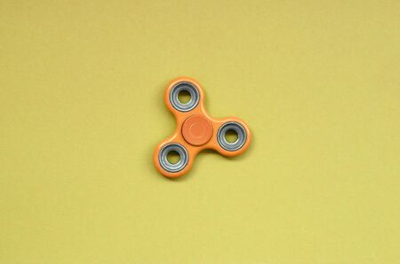 orange fidget spinner lies on texture background of fashion pastel orange color paper in minimal concept.の写真素材