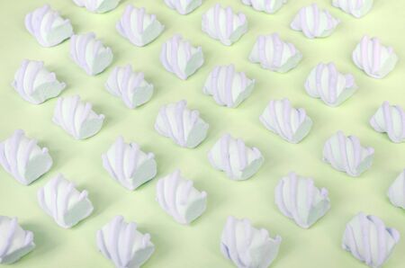 Colorful marshmallow laid out on lime paper background. pastel creative textured pattern. Perspective macro shot.の写真素材