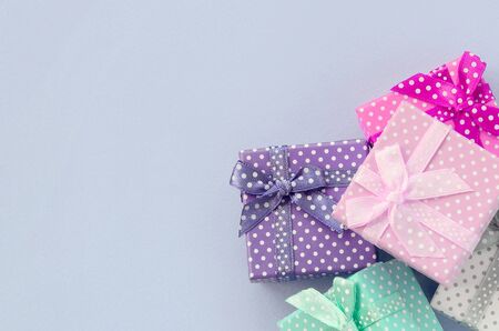 Pile of a small colored gift boxes with ribbons lies on a violet background. Minimalism flat lay top...