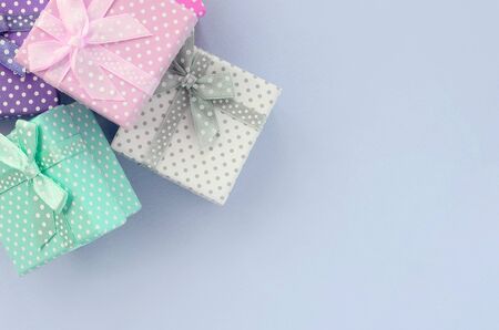 Pile of a small colored gift boxes with ribbons lies on a violet background. Minimalism flat lay top view.の写真素材