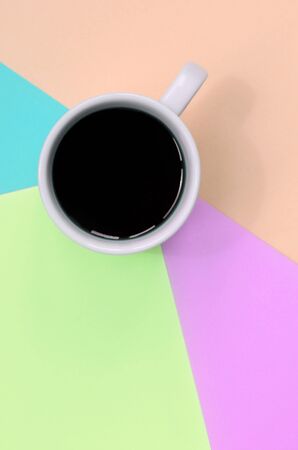 Small white coffee cup on texture background of fashion pastel pink, blue, coral and lime colors paper in minimal concept.の写真素材